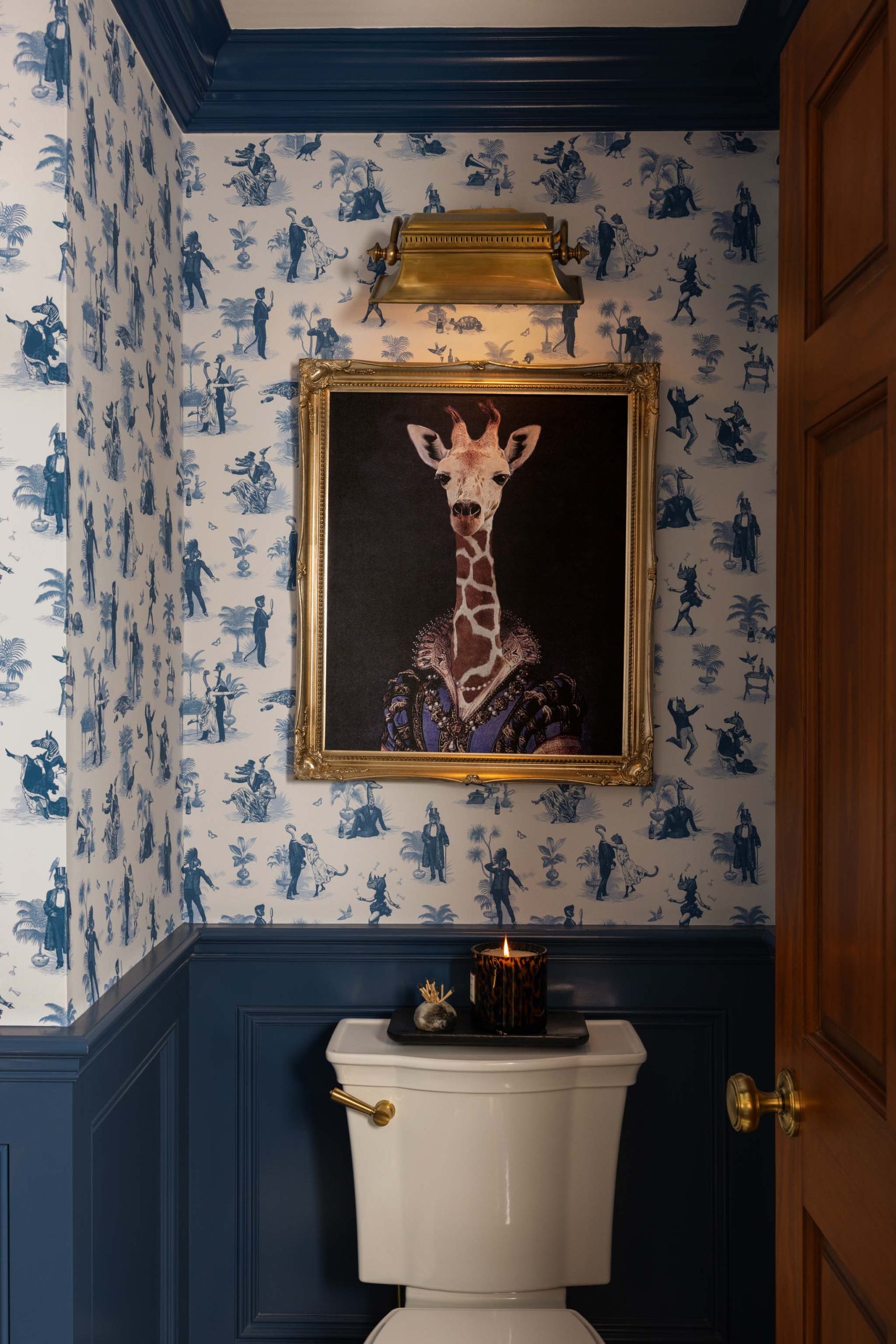 Whimsical English country powder room with blue toile wallpaper, lacquered millwork and statement art