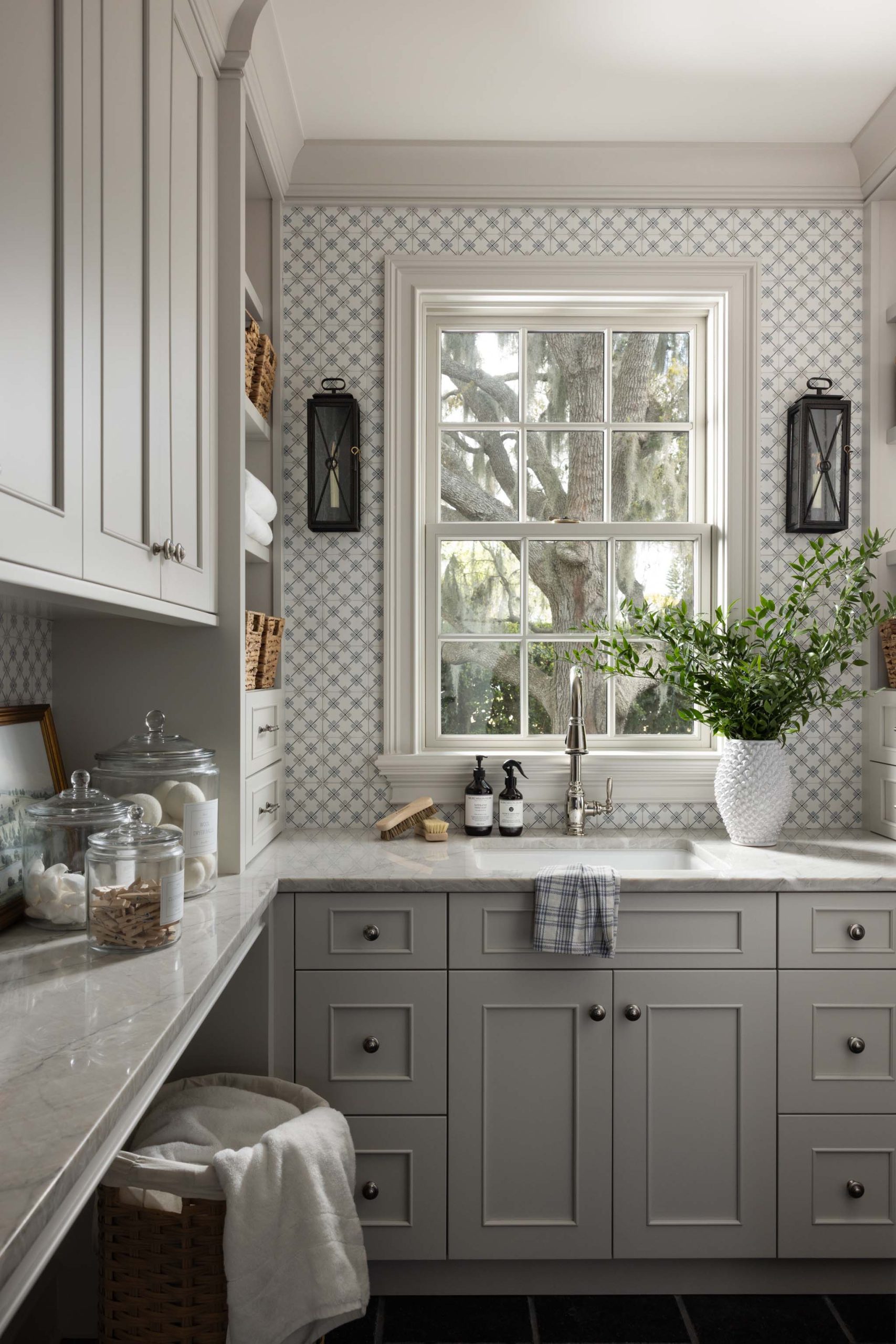 Traditional English laundry room with custom cabinetry, utility sink and patterned tile backsplash