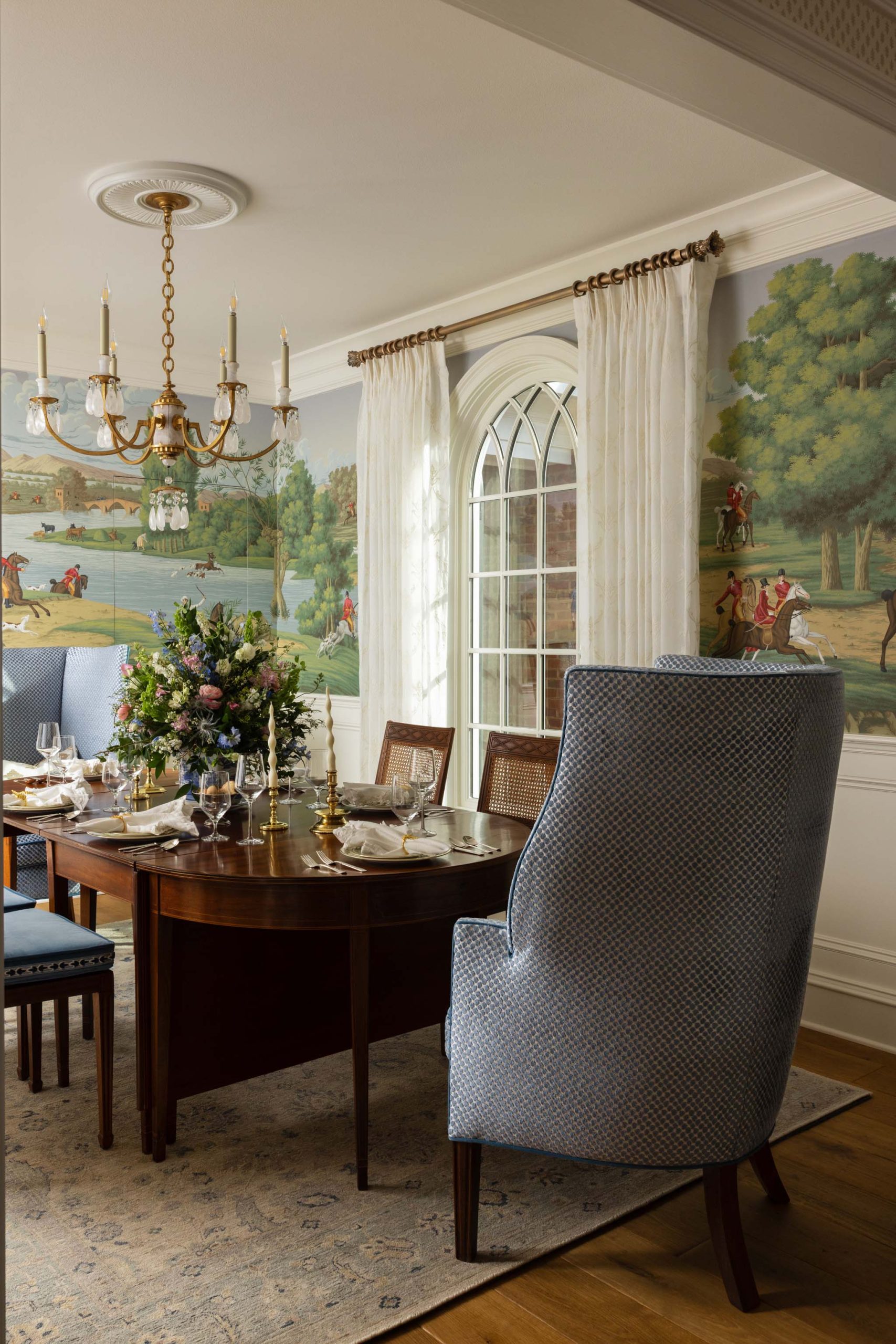Traditional English country dining room with blue wing chairs and arched window