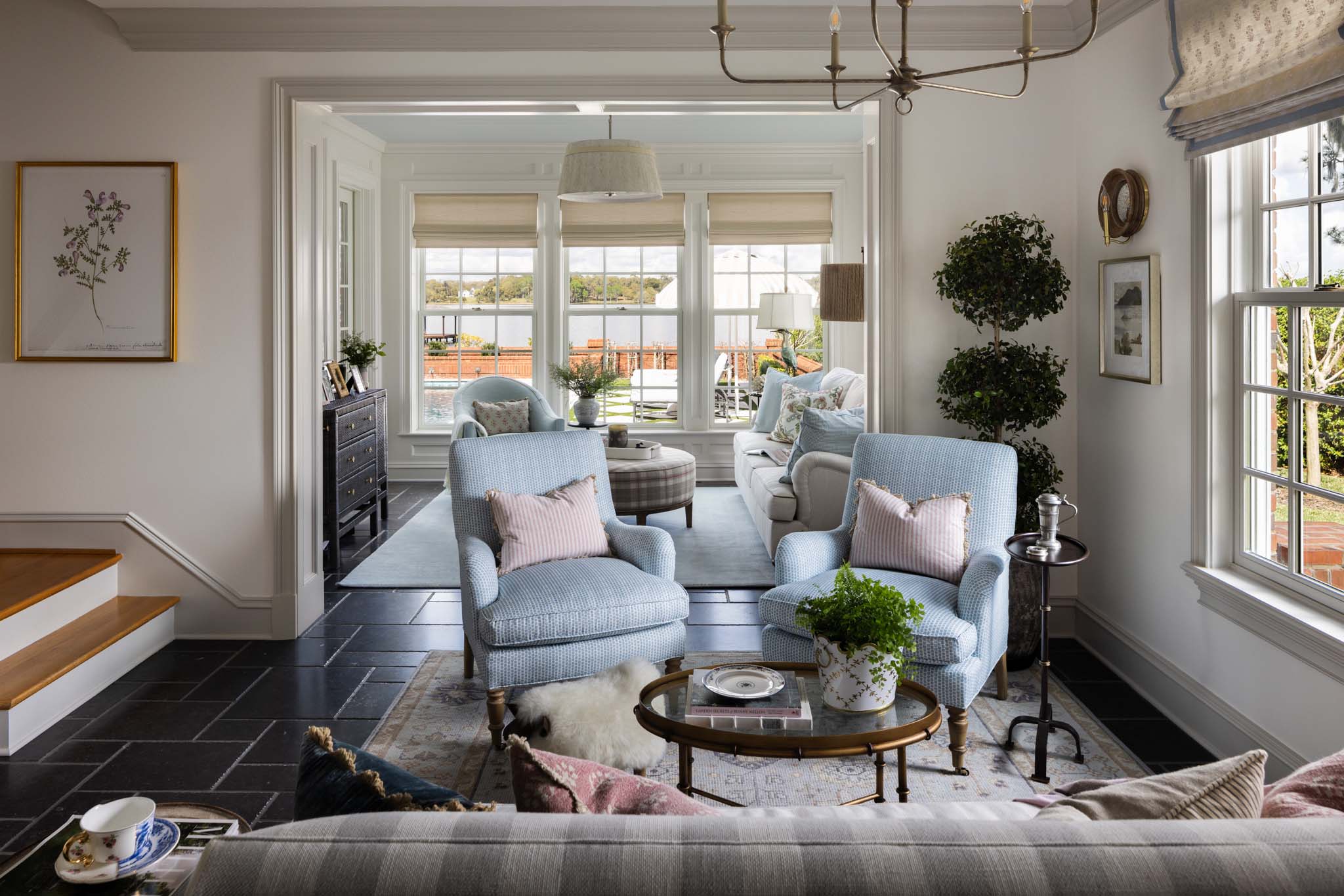 English country sitting room with blue upholstered chairs, Roman shades and lake view