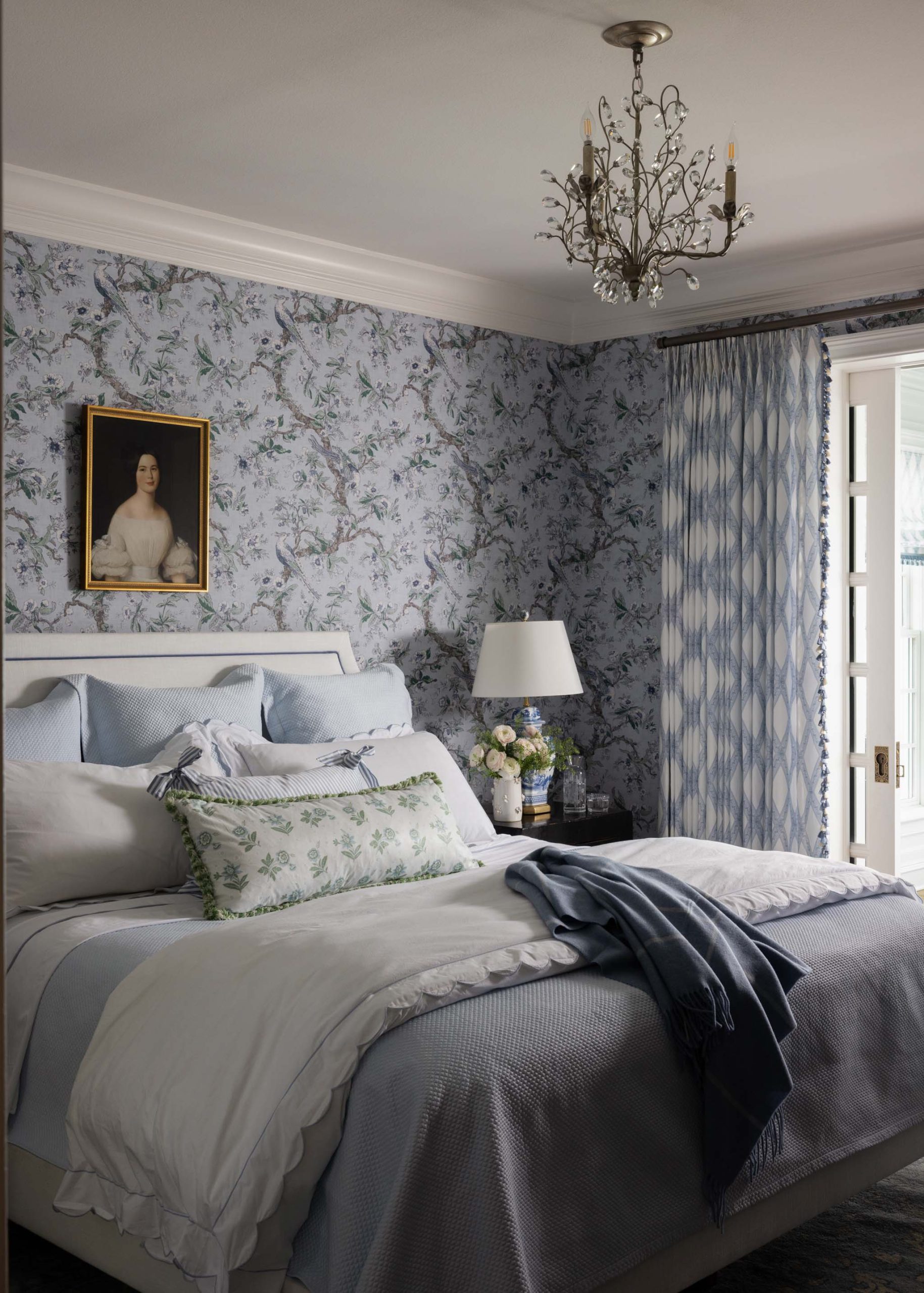 English country primary bedroom with upholstered bed, layered bedding and botanical wallpaper