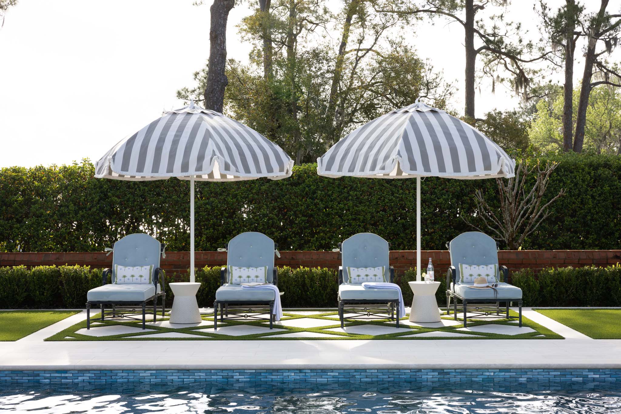 Luxury residential pool with blue lounge chairs and striped umbrellas
